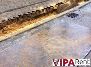 Eine Ueberfahrplatte aus Stahl liegt neben einem Tiefbaugraben um diesen abzudecken damit die Zufahrt befahrbar bleibt.